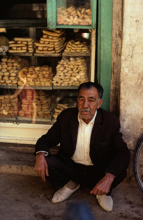 Man Squatting in front of Bakery Window, Iran