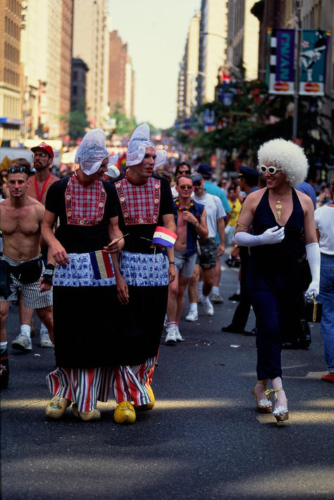 People in colorful costumes and wigs walking down a city street.