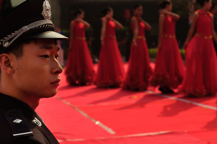 Cop with Red Dancers in Background, Pingyao