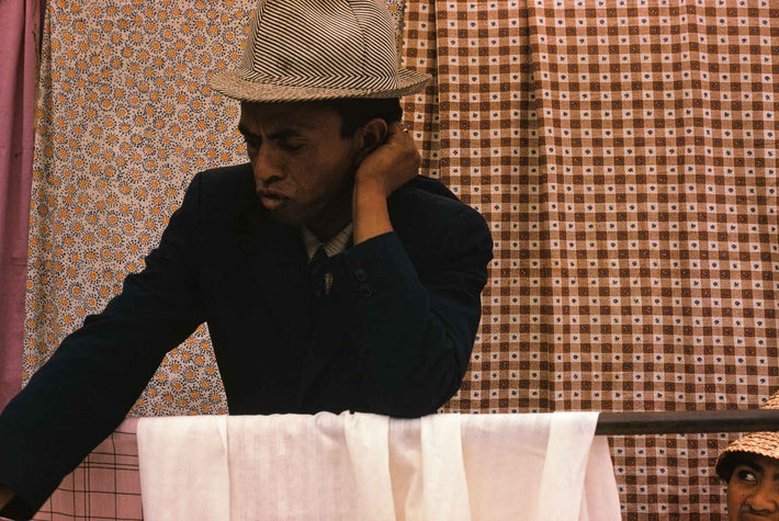 Man with Fabrics in Background, Antananarivo