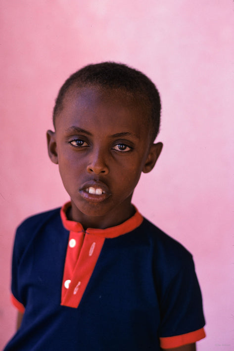 Young Boy in Blue and Red Against Pinkish Background, Somalia