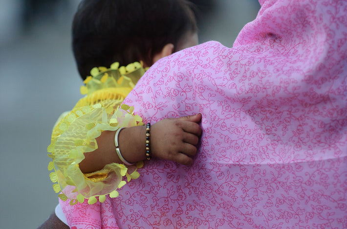 Baby in Yellow, Arm on Mom's Pink Head Scarf, Mumbai