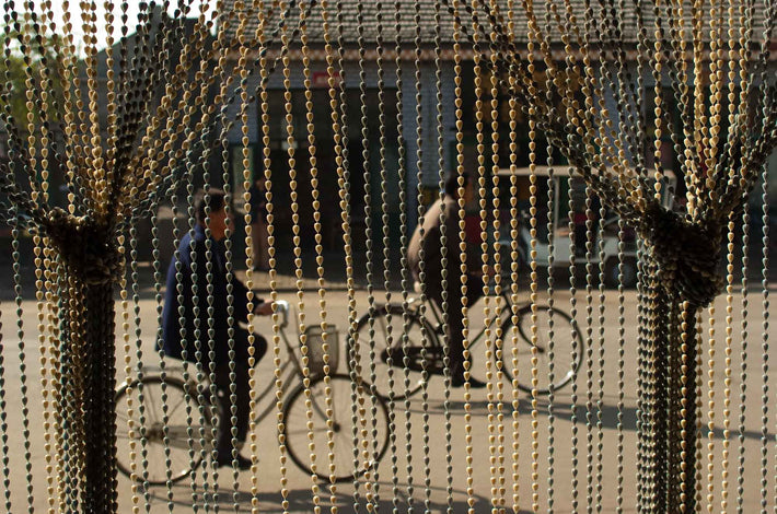 Two Bicyclists through Beaded Curtain, Pingyao